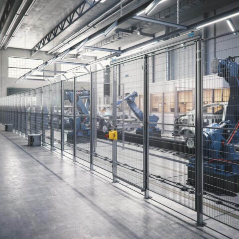 Automated robotic arms working behind Troax machine guarding in a high-tech industrial manufacturing facility