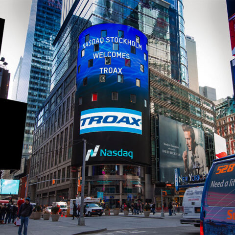 Troax welcomed by NASDAQ Stockholm on a digital billboard in a bustling city scene, showcasing the brand's reach and presence in the global market.