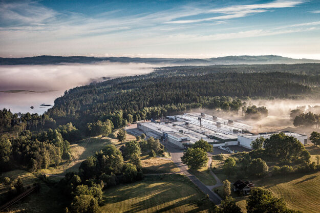 An aerial view of the Troax facility surrounded by a forest landscape with morning mist over the trees in Tyngel, Hillerstorp, Småland.